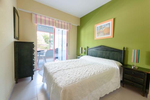 a bedroom with green walls and a bed and a table at Apartamentos Nuevo México C 432 in Calpe