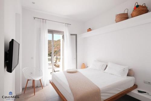 a white bedroom with a bed and a window at Cavo Milos in Adamantas