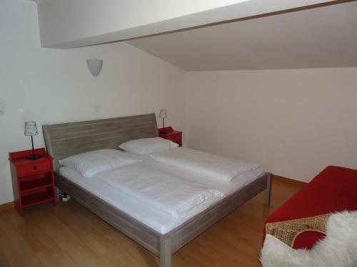 a bedroom with a bed with white sheets and two night stands at Schlossalm Appartement in Bad Hofgastein