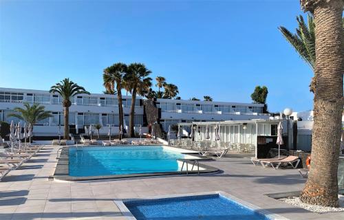 een resort met een zwembad en palmbomen en een gebouw bij Apartamentos Arena Dorada in Puerto del Carmen