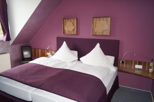 ein lila Schlafzimmer mit einem großen Bett mit weißer Bettwäsche in der Unterkunft Bio-Weingut, Gästehaus und Kräuterhof in Flomborn