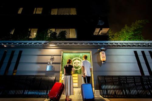 two people standing in front of a building with their luggage at Hauza Kyoto Gojo Karasuma in Kyoto