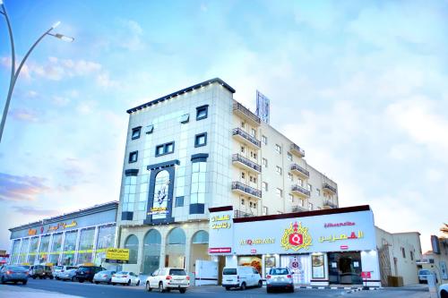 ein hohes weißes Gebäude mit davor geparkt in der Unterkunft سكون سويت للشقق الفندقية in Ha'il