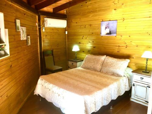 1 dormitorio con 1 cama en una pared de madera en Los Quetzales, en Maldonado