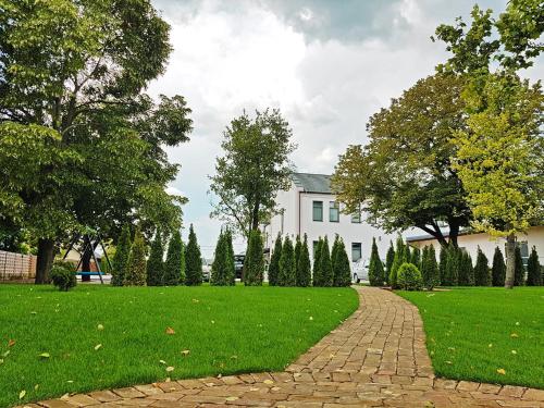 a brick walkway in front of a white house at Hotel Czinege & Étterem in Kóka