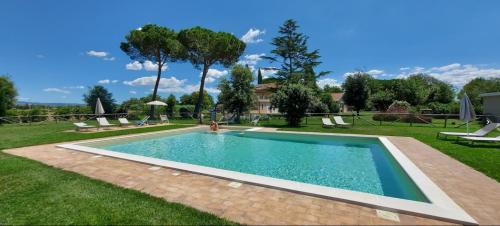 a swimming pool in a yard with chairs and trees at Agriturismo Poderedodici in Orbetello