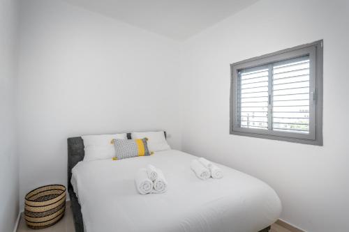 a white bed in a room with a window at Superb 1,5 BDR W balcony close to the beach in Tel Aviv