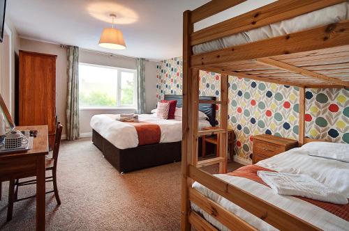 a bedroom with two bunk beds and a desk and a desk at The Twice Brewed Inn in Bardon Mill
