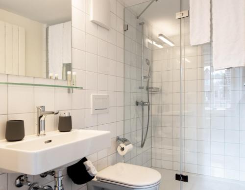 La salle de bains blanche est pourvue d'un lavabo et de toilettes. dans l'établissement Haus am Schlossberg, à Laufenburg