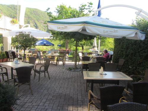 a patio with tables and chairs and an umbrella at Weinhaus Berg in Bremm