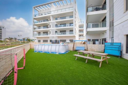 a picnic table and a basketball hoop on a lawn in front of a building at Stylish Garden Apartment Close to Akhziv Beach by Sea N' Rent in Nahariyya