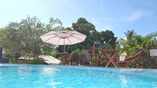a group of chairs and an umbrella next to a swimming pool at Pousada Tubarão in Arraial d'Ajuda