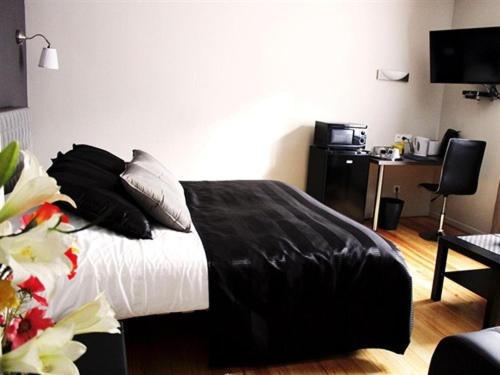a bedroom with a bed with black sheets and pillows at Villa Louvre Lens in Lens