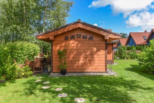 a wooden shed with a sun written on it in a yard at Guest House Pasaulio Krastas in Palanga