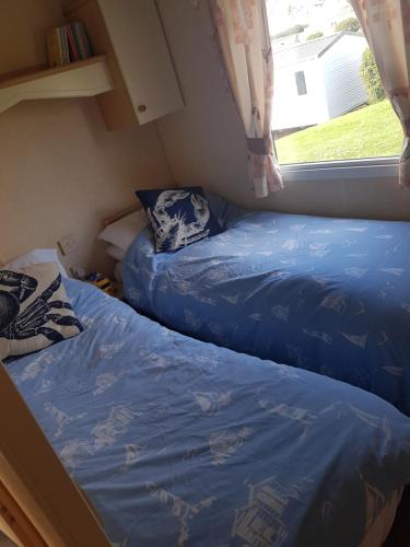 two beds in a small room with a window at Haven Devon Cliffs Caravan in Budleigh Salterton