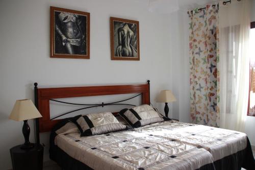 a bedroom with a bed with two pictures on the wall at Balcon del Mar en la Costa in Costa Del Silencio