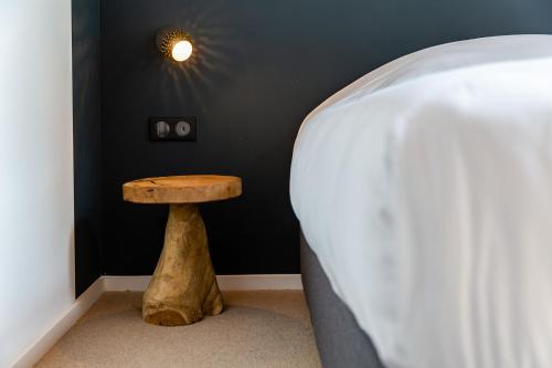 a bed with a wooden stool next to a wall at HARAS DE BARRY in Sainghin-en-Mélantois