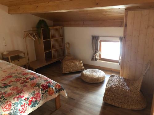 um quarto com uma cama e cadeiras de vime e uma janela em La Maisonnette auvergnate em Vertaizon