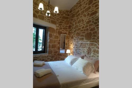 a bedroom with a large bed with a stone wall at Traditional stone house in Sitia