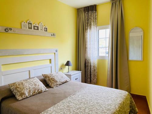 a bedroom with a bed with yellow walls and a window at Rosamar in Los Cristianos