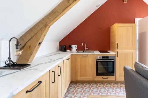an attic kitchen with wooden cabinets and a staircase at HARAS DE BARRY in Sainghin-en-Mélantois