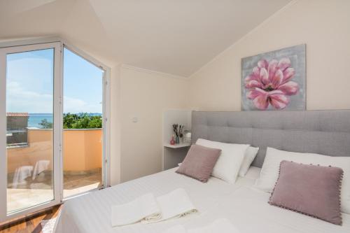 a bedroom with a white bed with a large window at Apartments Medanić - Private Pool in Privlaka