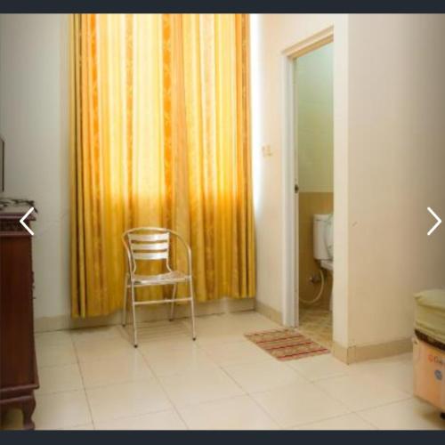 a chair in a room with a curtain and a toilet at Penginapan Sriwijaya in Tanjungpandan