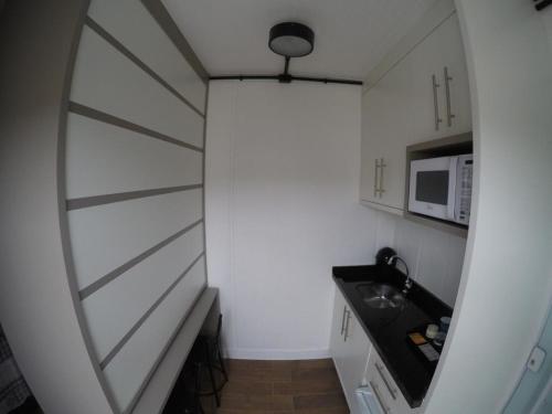 a small kitchen with a white wall and a microwave at Vila Container in Penha