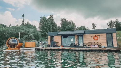 a tiny house on a dock next to a body of water at Costa del Kryspi Całoroczne Domy na Wodzie in Cholerzyn
