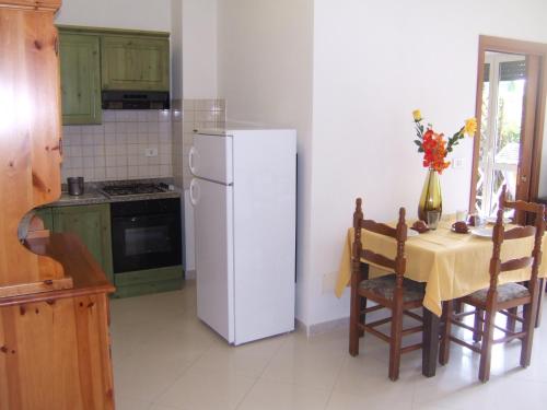a kitchen with a table with a white refrigerator at Hotel Pompeo Residence in Castellabate