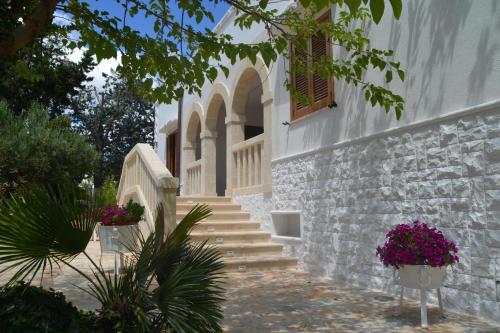 a white building with stairs and flowers in pots at Agriturismo Salinola in Ostuni