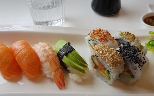 a plate of sushi and vegetables on a table at The Cozy Little House in Motala