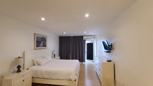 um quarto branco com uma cama e uma televisão em Stardust Hotel em Miami Beach