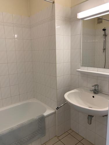 a white bathroom with a sink and a bath tub at Koksijde Zeelaan Appartement A4 in Koksijde