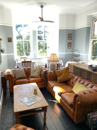 a living room with brown leather couches and a table at The Devonian in Ilfracombe