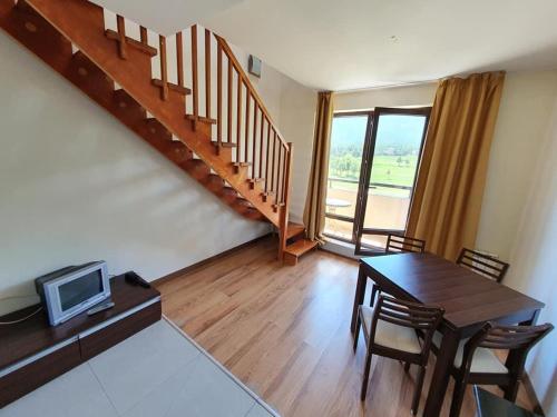 a living room with a dining room table and a staircase at Sunny duplex with spectacular view in Terra Complex in Razlog