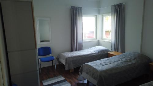 Pokój z 2 łóżkami, niebieskim krzesłem i oknem w obiekcie Seitsemän sillan majatalo w mieście Eugmo