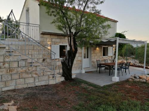 Cette maison dispose d'une terrasse avec une table et un arbre. dans l'établissement Olive Grove House Lumbarda, à Lumbarda