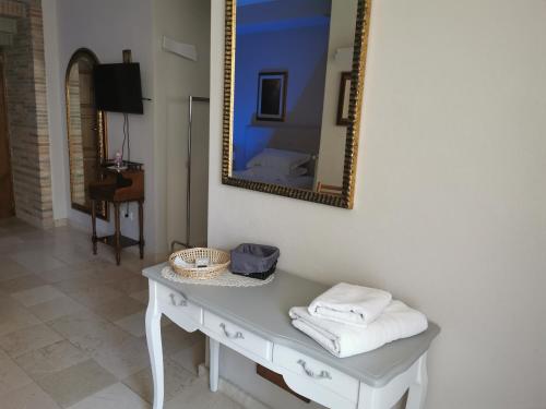 un espejo en una pared sobre una mesa con toallas en B&B Casa Dilillo, en Foggia