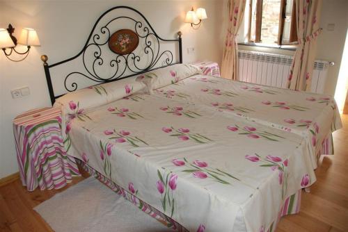 a bedroom with a bed with pink flowers on it at Pazo Santa María in Arzúa
