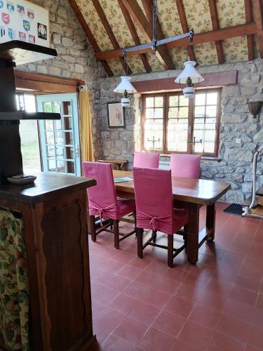 une salle à manger avec des chaises roses et une table en bois dans l'établissement Ferienhaus Cottage Maison typique, à Brignogan-Plage