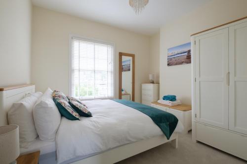 una camera da letto con un grande letto bianco con cuscini di Serene in Ryde a Ryde