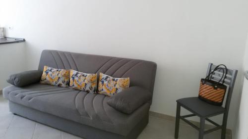 a gray couch with pillows and a chair in a room at Mio & Tuyo Casa Vacanze in Carloforte