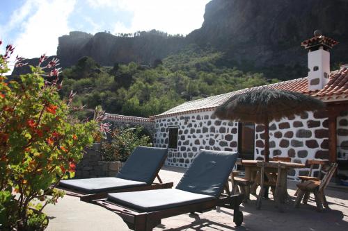 a patio with two chairs and a table and an umbrella at Casa Rural Isla de Cuba in Tejeda