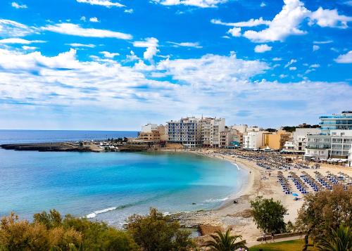 a beach with umbrellas and chairs and the ocean at Amena Mar Hotel in Sa Coma