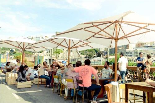 a group of people sitting at tables under umbrellas at Apartamento com Hidro in Belo Horizonte