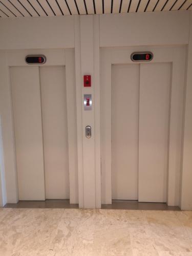 a row of four white elevator doors in a building at Zeester en koffie. in Oostduinkerke-Bad