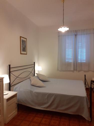 a bedroom with a bed with white sheets and a window at Terrazza sul Mare holidays with experiences in Lipari