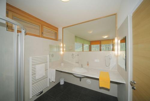 a bathroom with a sink and a large mirror at Vitalhotel Rainer in Ultimo