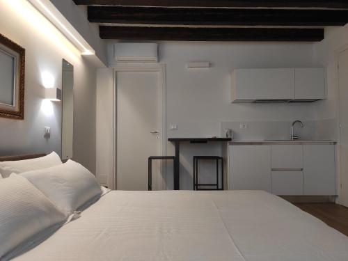 1 dormitorio con 1 cama blanca y cocina en Borgo di Ponte Holiday Apartments & Rooms, en Cividale del Friuli
